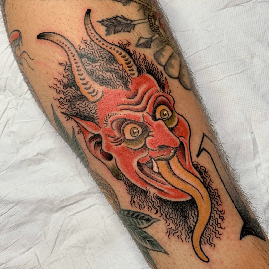 Tatuaggio in stile traditional, a colori, di un demone dalla lingua gialla, realizzato da Andrea Cartabia,Water Law Tattoo Pro Team Artist