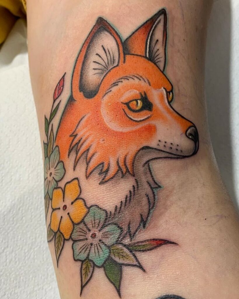 Artista: Andrea Cartabia. Pro Team Artist Water Law Tattoo. Tatuaggio a colori di una testa di volpe con al collo una ghirlanda di fiori colorati.