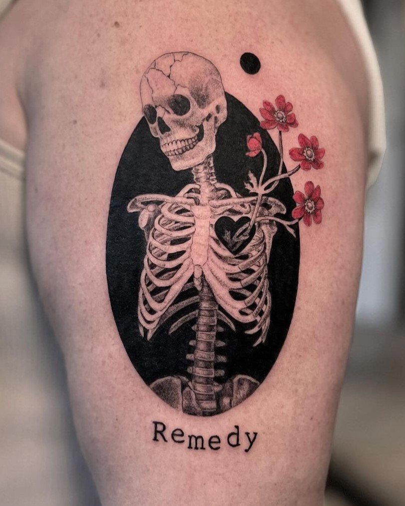 Tatuaggio realistico in bianco e nero di uno scheletro che tiene in mano dei fiorellini rossi. Realizzato dall’artista La Gatta.